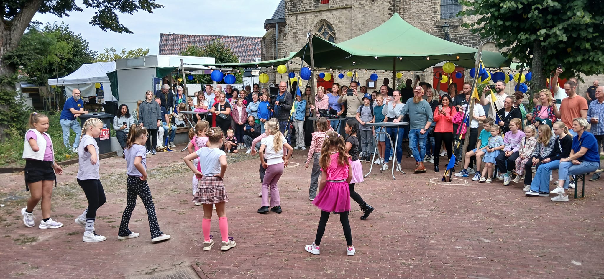 Dansende kinderen op het kerkplein tijdens een feest in Wehl