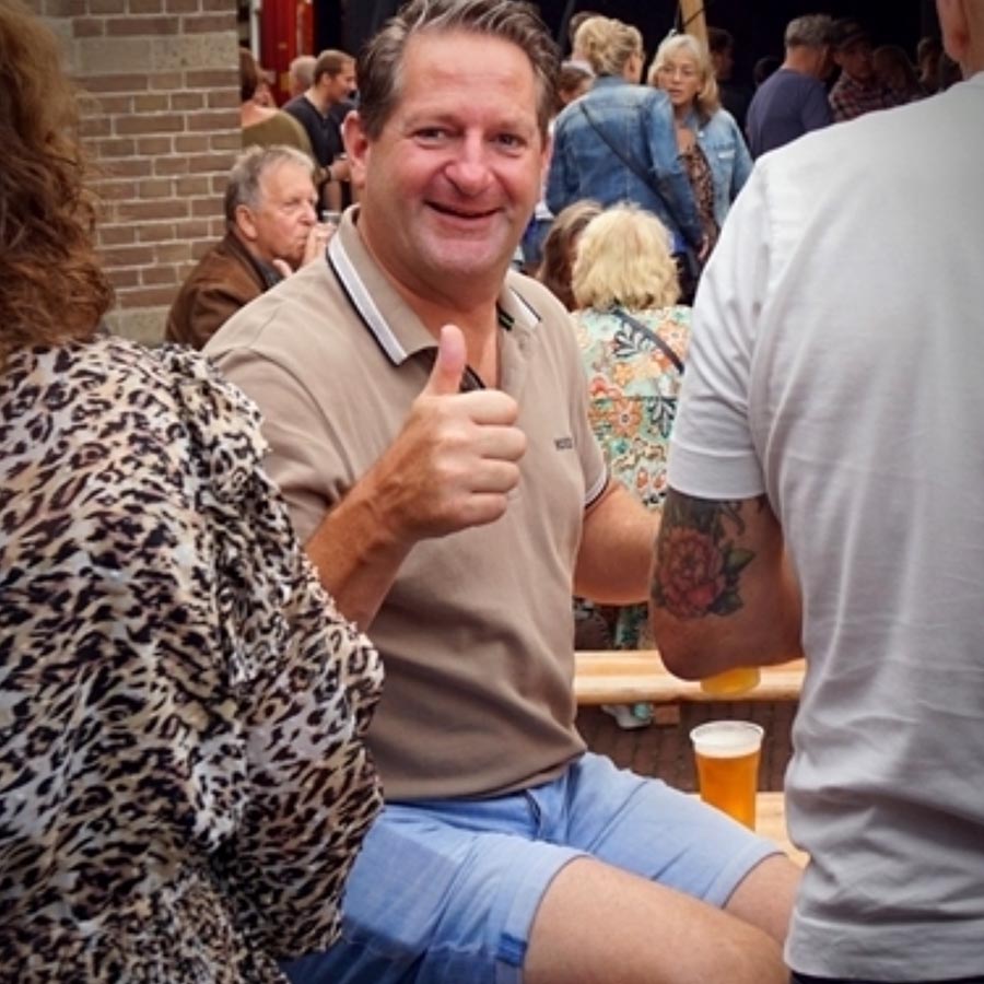 Lachende man steekt duim op tussen feestgangers in Wehl